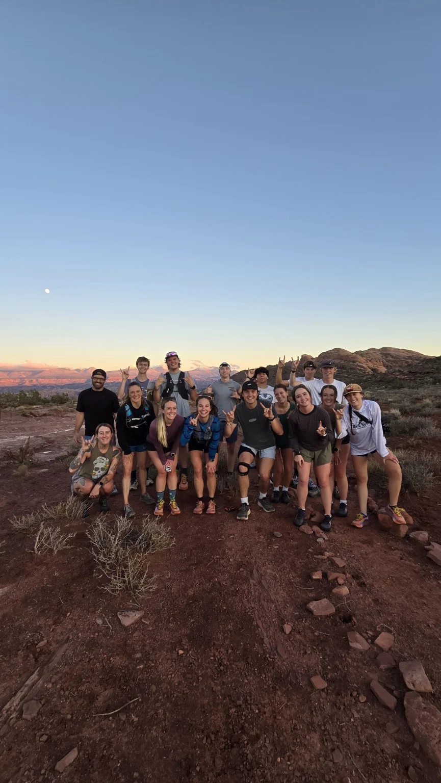 Runners gathered on a rocky trail at dusk